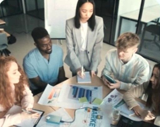 A diverse marketing team gathered around a table reviewing printed data charts and business plans during a strategy session.